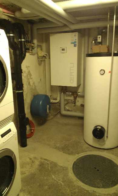 Hauswirtschaftsraum im Keller mit Warmwasserbereiter, Heizkessel, Rohrleitungen und Waschmaschine.
