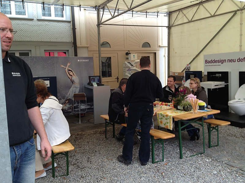 Menschen stöbern an den Ständen eines Marktstandes unter einem zeltartigen Dach.