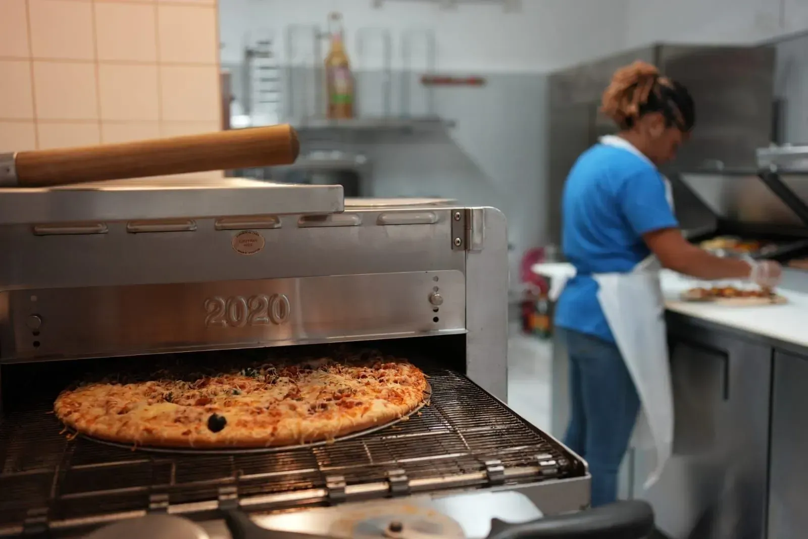 Cuisson de pizzas dans un four de restaurant, avec un chef travaillant en cuisine
