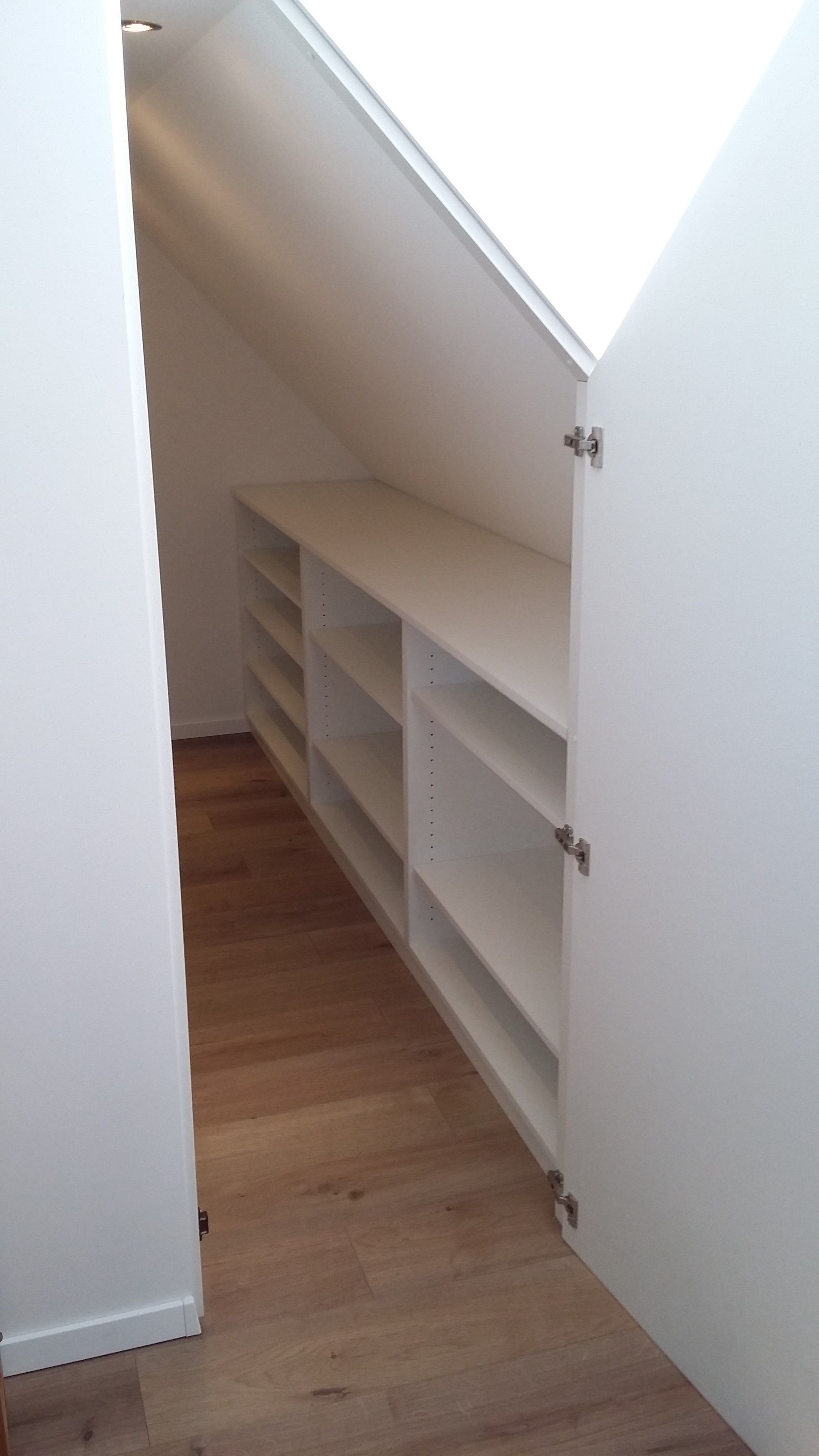 Ein begehbarer Kleiderschrank mit Dachschräge und Regalen