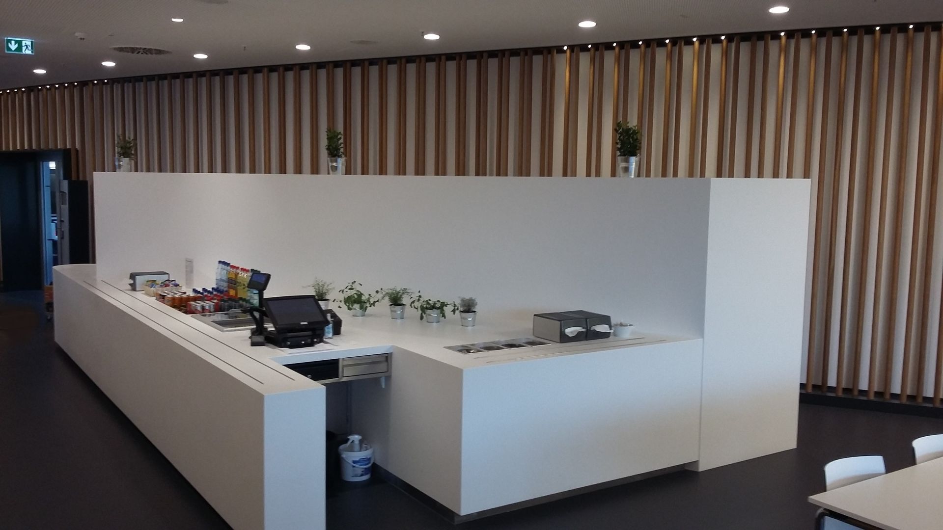 Eine lange weiße Theke in einem Raum mit Tischen und Stühlen.