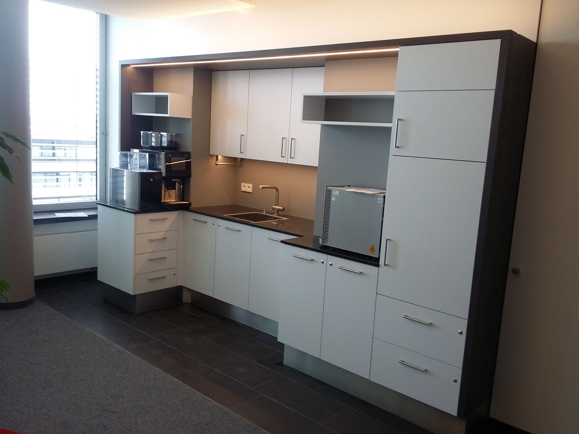 Eine Küche mit weißen Schränken und schwarzen Arbeitsplatten