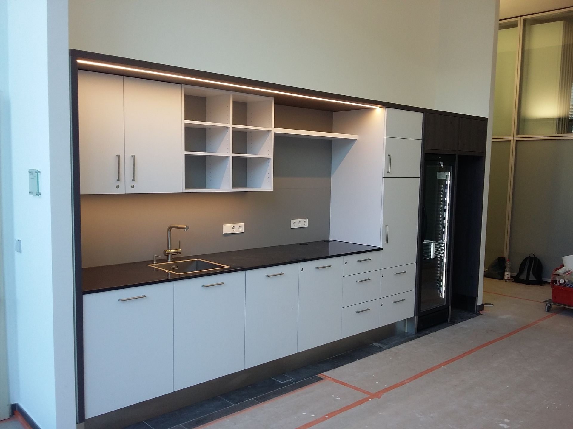 Eine Küche mit weißen Schränken und schwarzen Arbeitsplatten