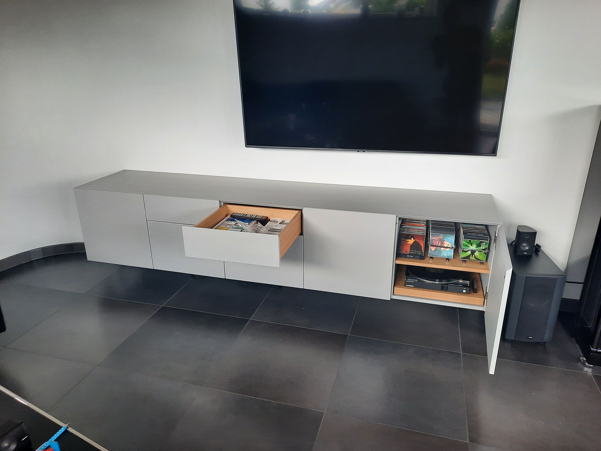 Ein Wohnzimmer mit einem Fernseher und einem Regal mit einer offenen Schublade.