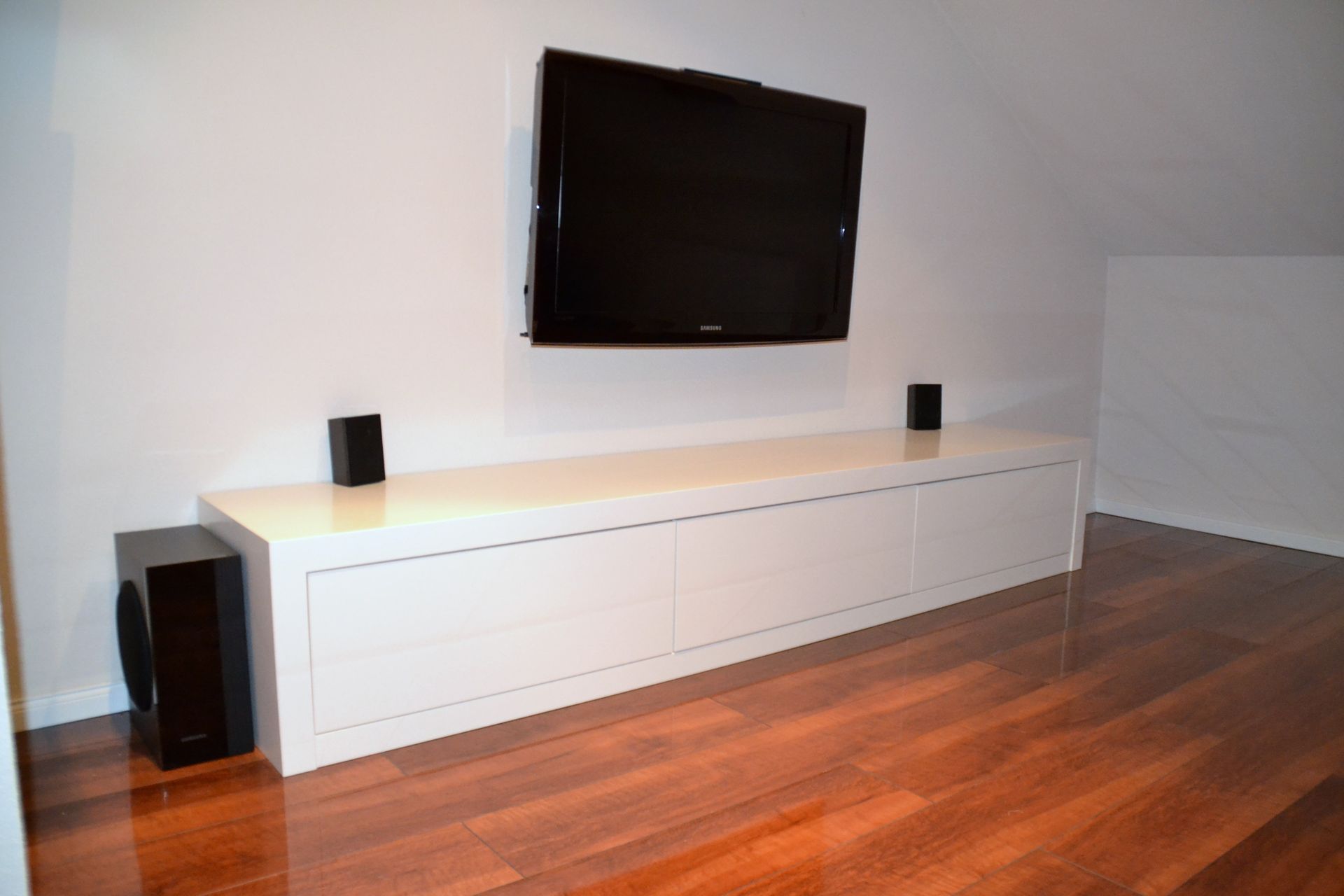 Ein weißes Entertainment-Center mit einem an der Wand montierten Flachbildfernseher