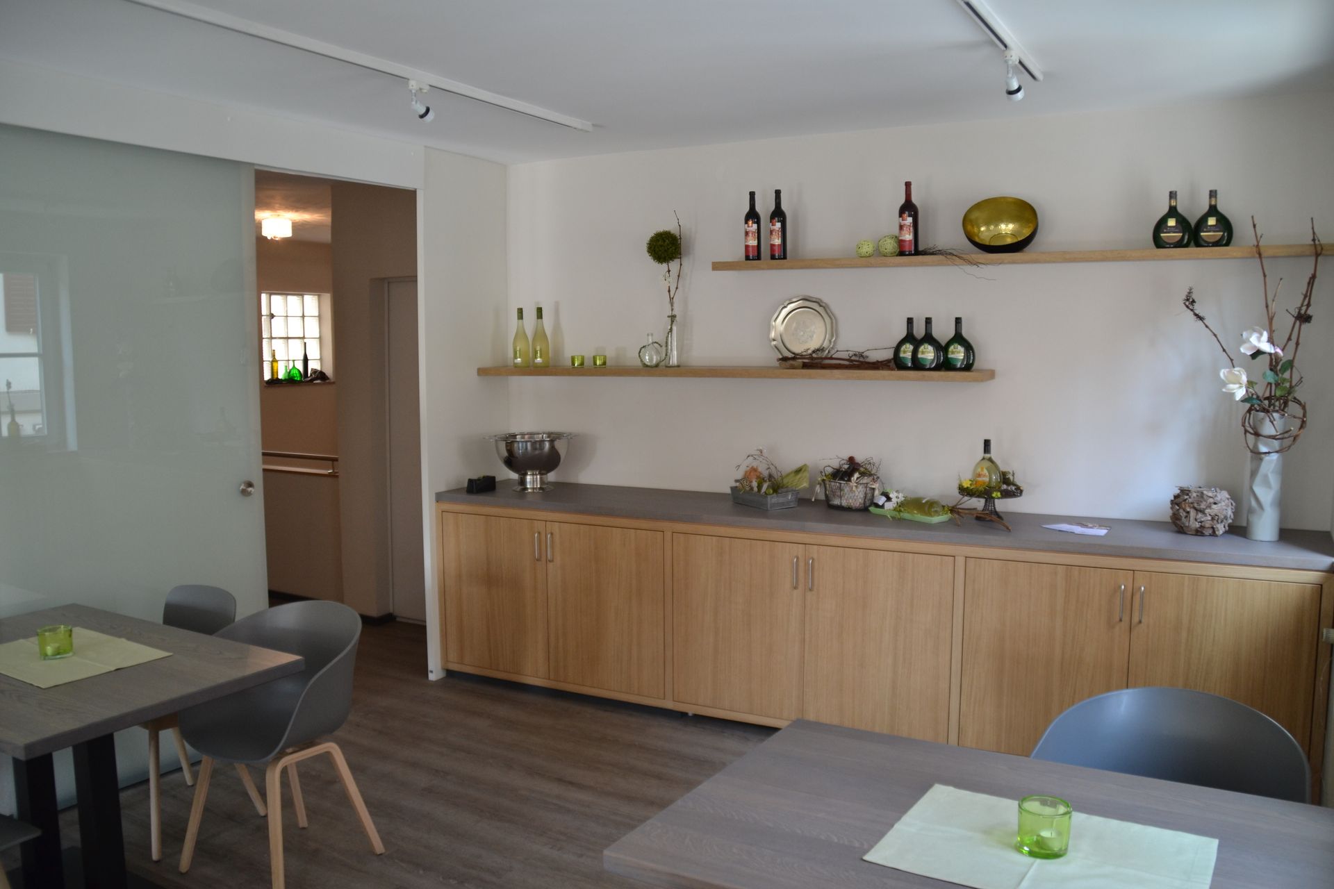 Ein Esszimmer mit Tischen und Stühlen und Regalen mit Flaschen darauf.