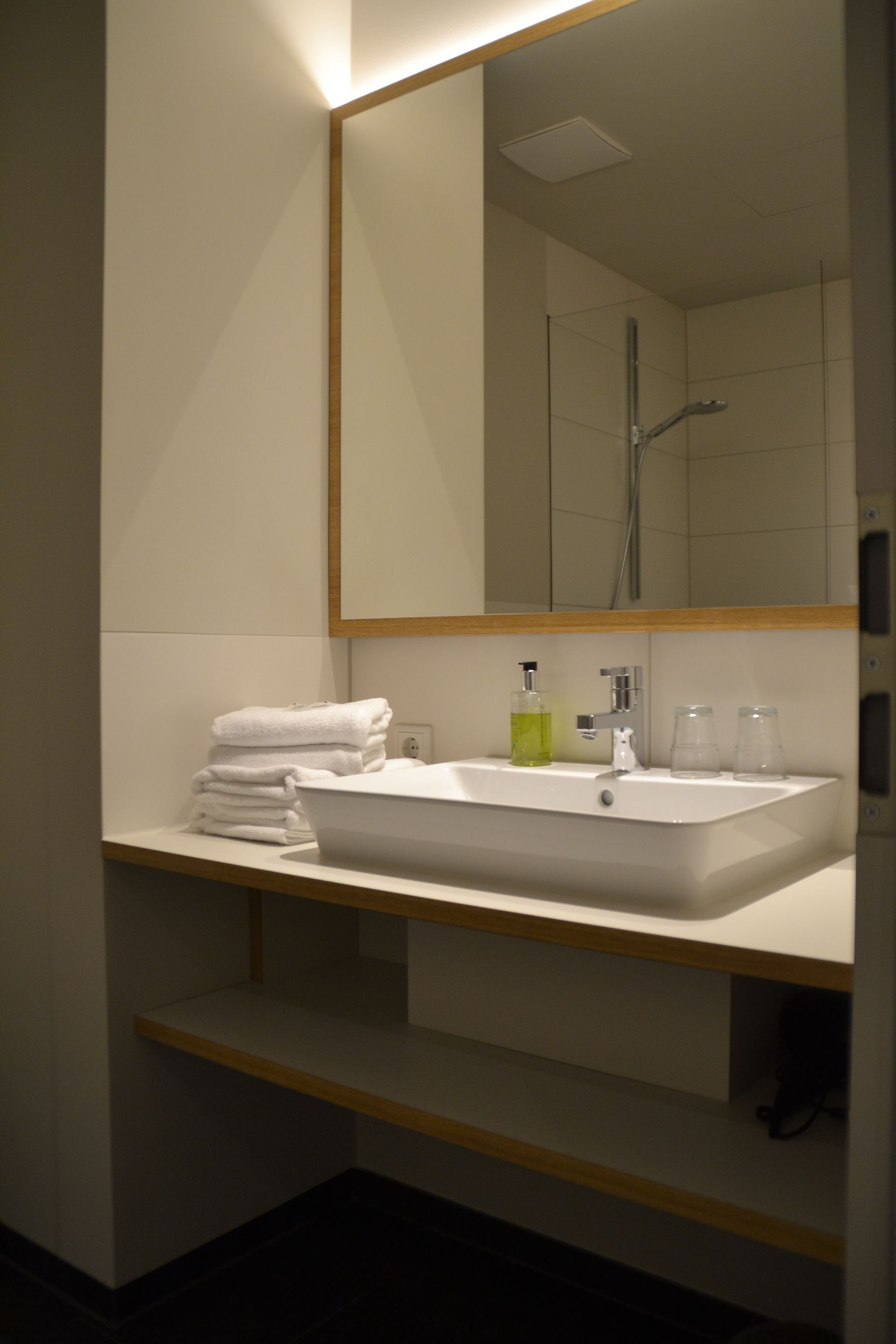 Ein Badezimmer mit Waschbecken, Spiegel und Handtüchern auf der Ablage.