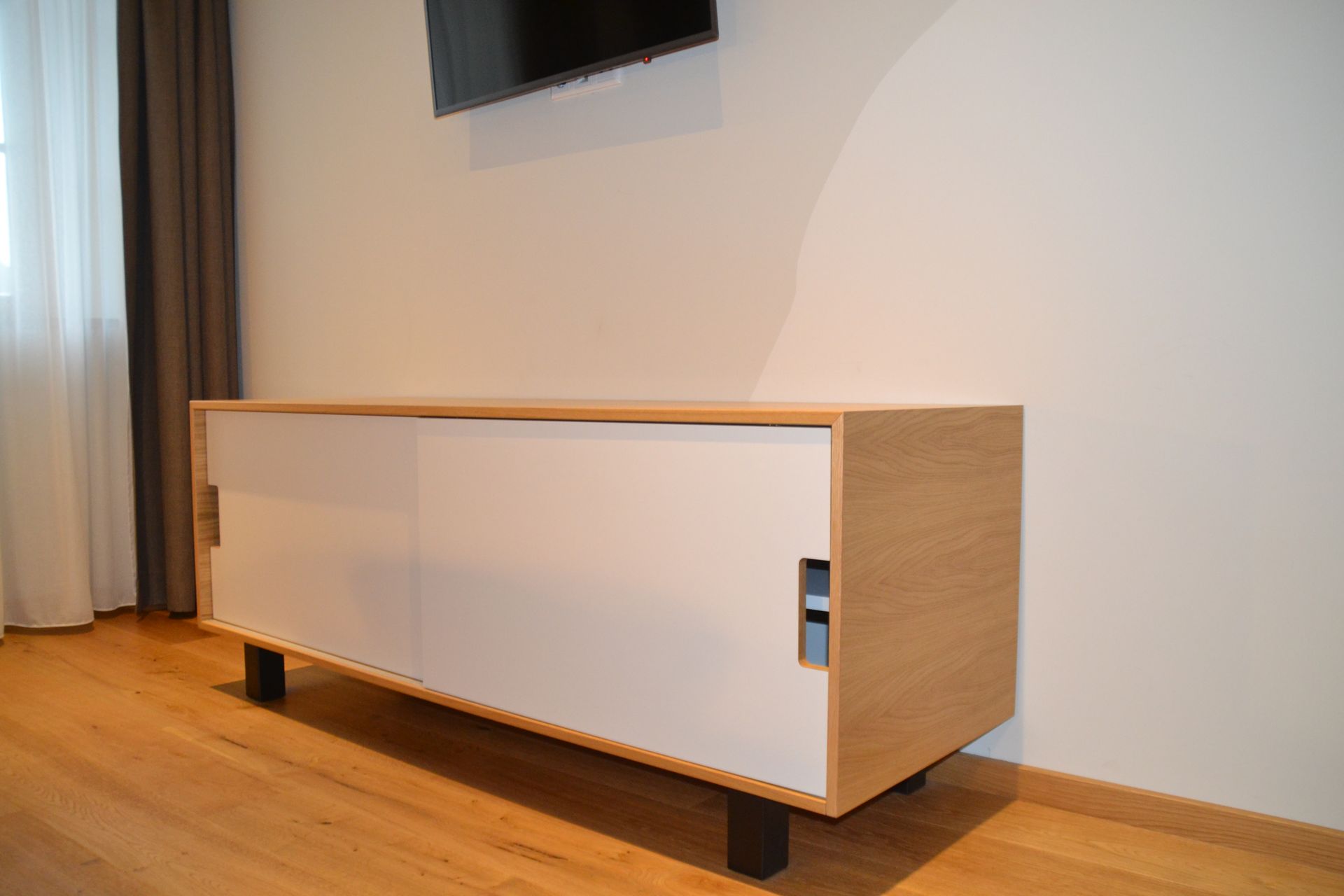 Ein Entertainment-Center aus Holz mit einem an der Wand montierten Fernseher.