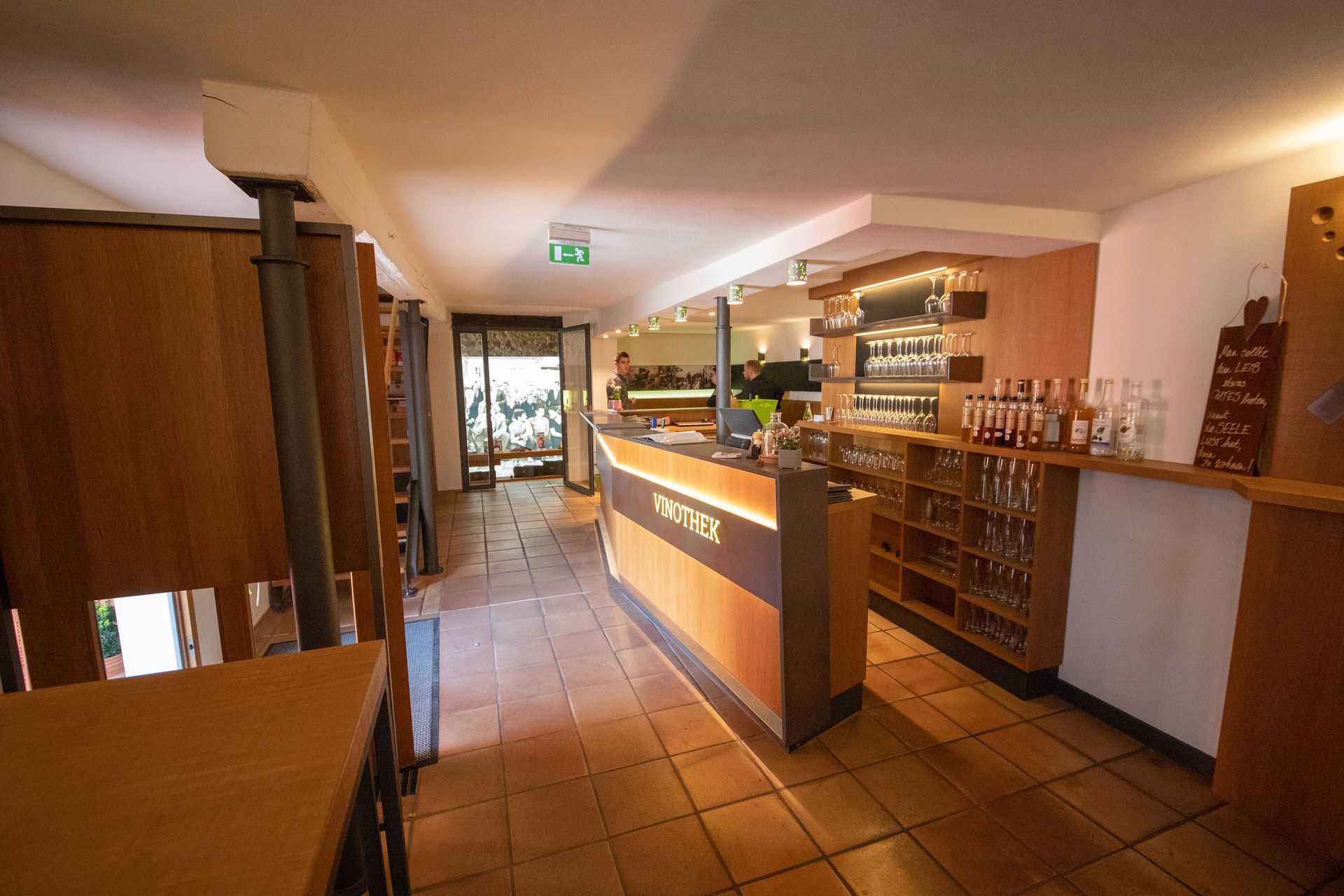 Ein Restaurant mit einer Holztheke sowie Tischen und Stühlen.