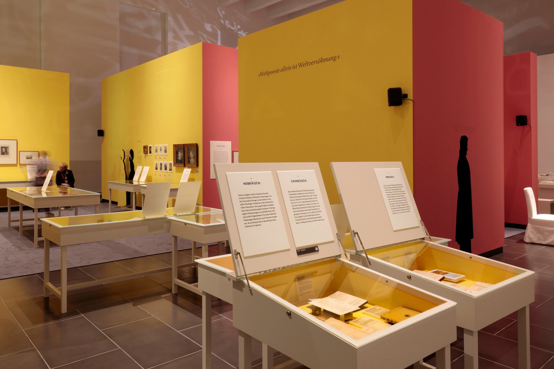 Ein Raum mit vielen Tischen und einer rosa Wand.