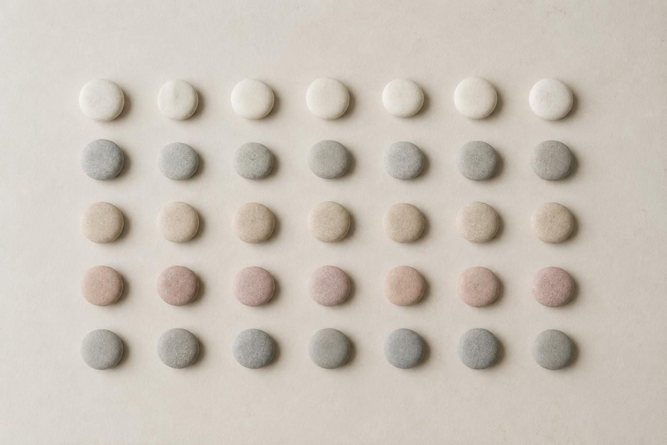 Cinco filas de pequeñas tabletas redondas de diferentes colores dispuestas en una cuadrícula