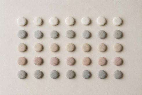Cinco filas de pequeñas tabletas redondas de diferentes colores dispuestas en una cuadrícula 