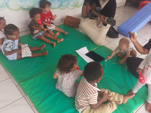 Des enfants sont allongés en cercle, les mains jointes, sur un tapis aux couleurs de l'arc-en-ciel