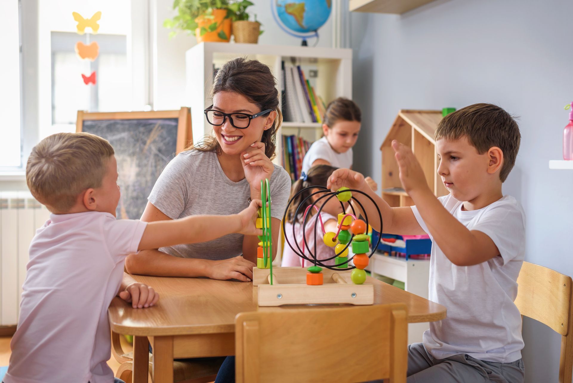 Une enseignante et des enfants jouent avec des jouets éducatifs à une table