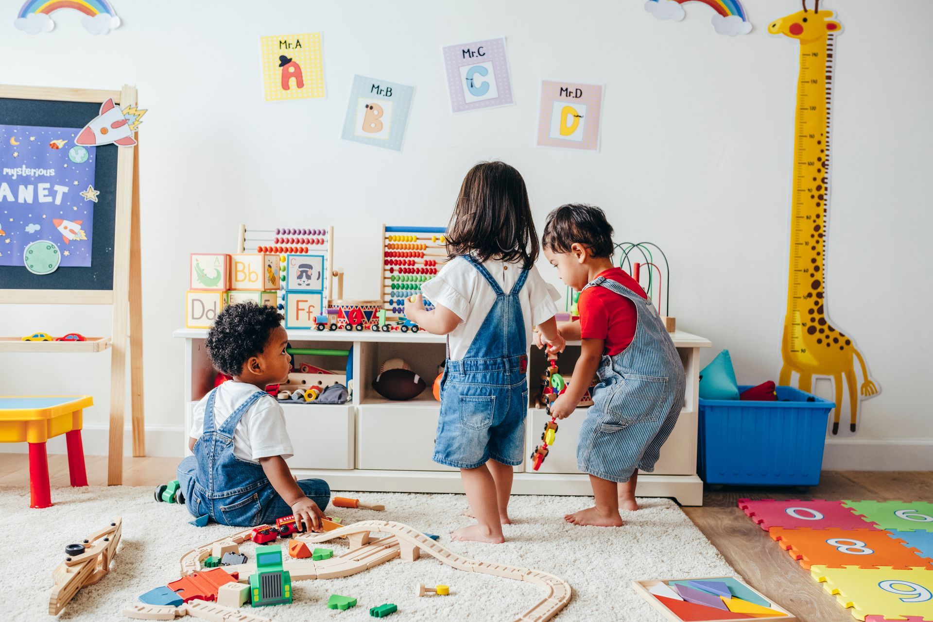 Des enfants jouent avec un petit train en bois dans une crèche