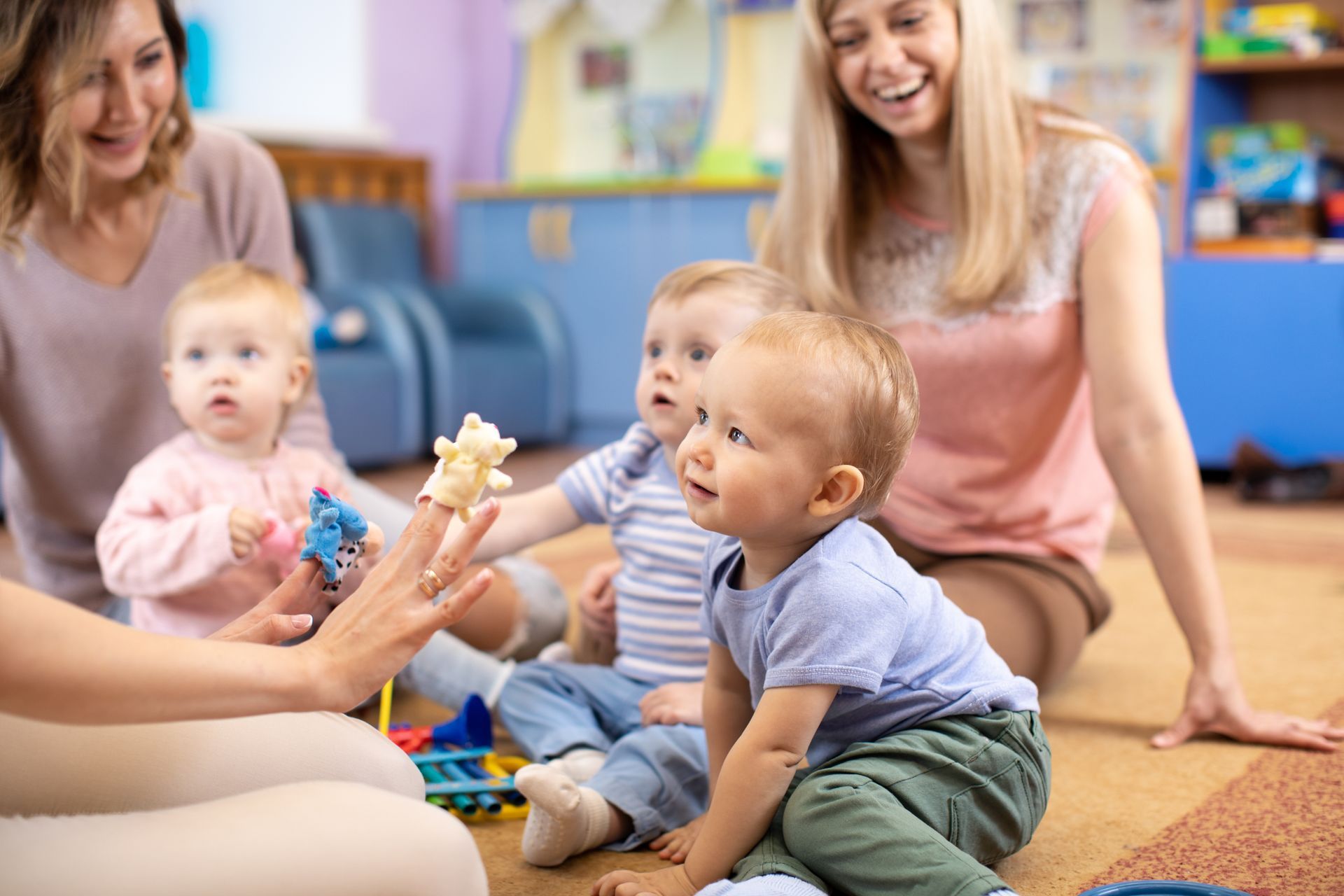 Une animatrice utilise des petites marionnettes sur ses doigts pour divertir des enfants dans une crèche