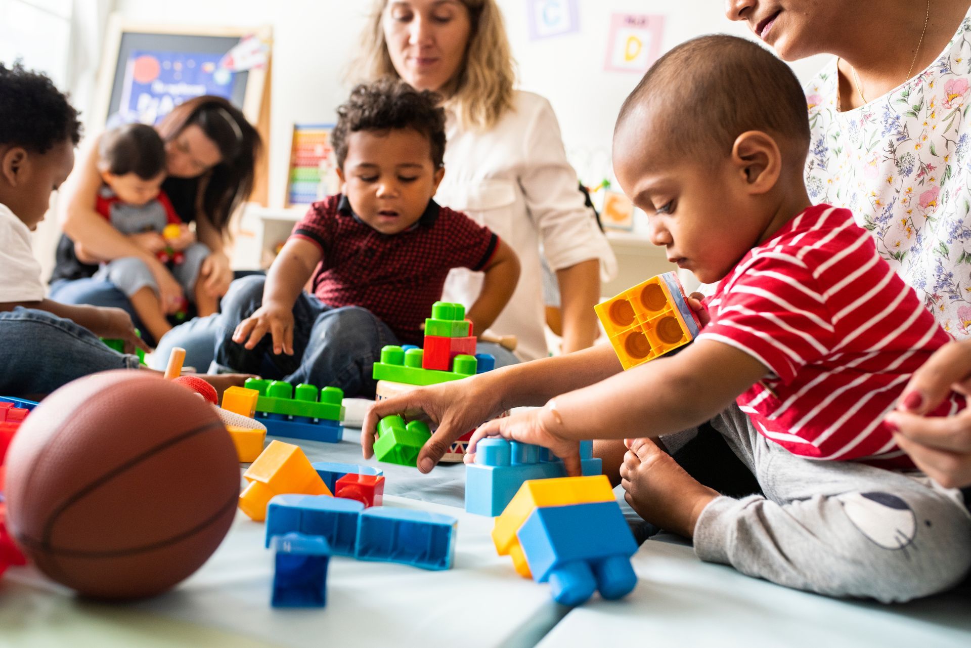Des enfants jouent avec des blocs empilables colorés sur le sol