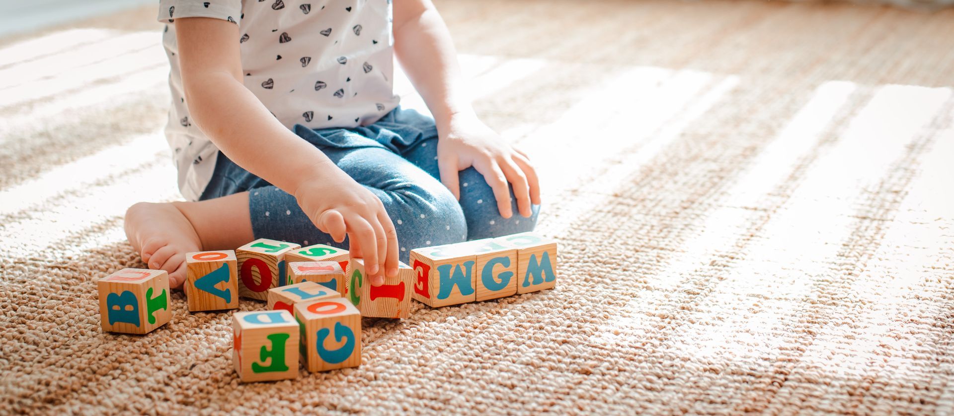 Enfant jouant avec des cubes en bois sur lesquels sont gravées les lettres de l'alphabet
