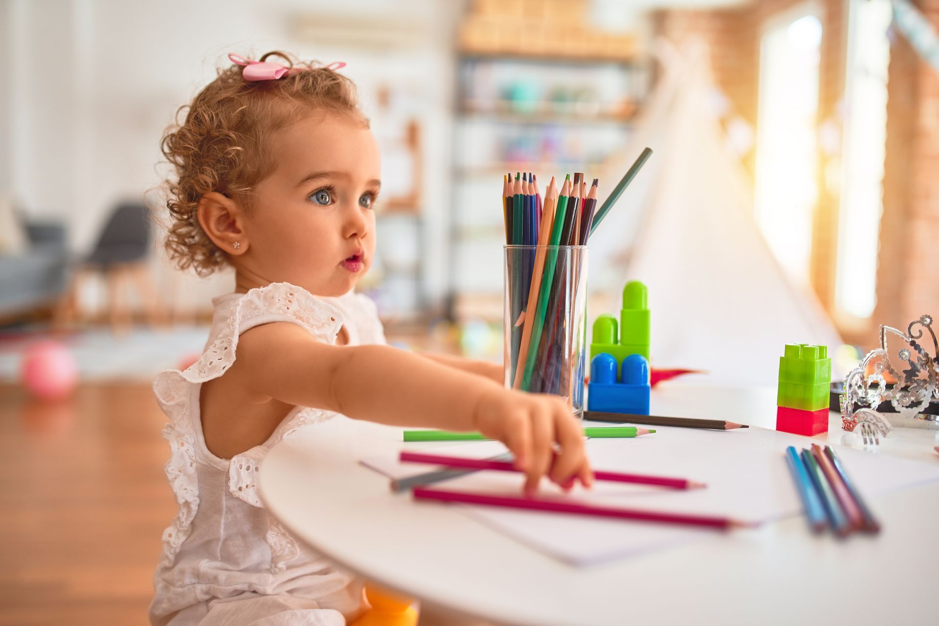 Enfant dessinant à une table blanche avec des crayons de couleur