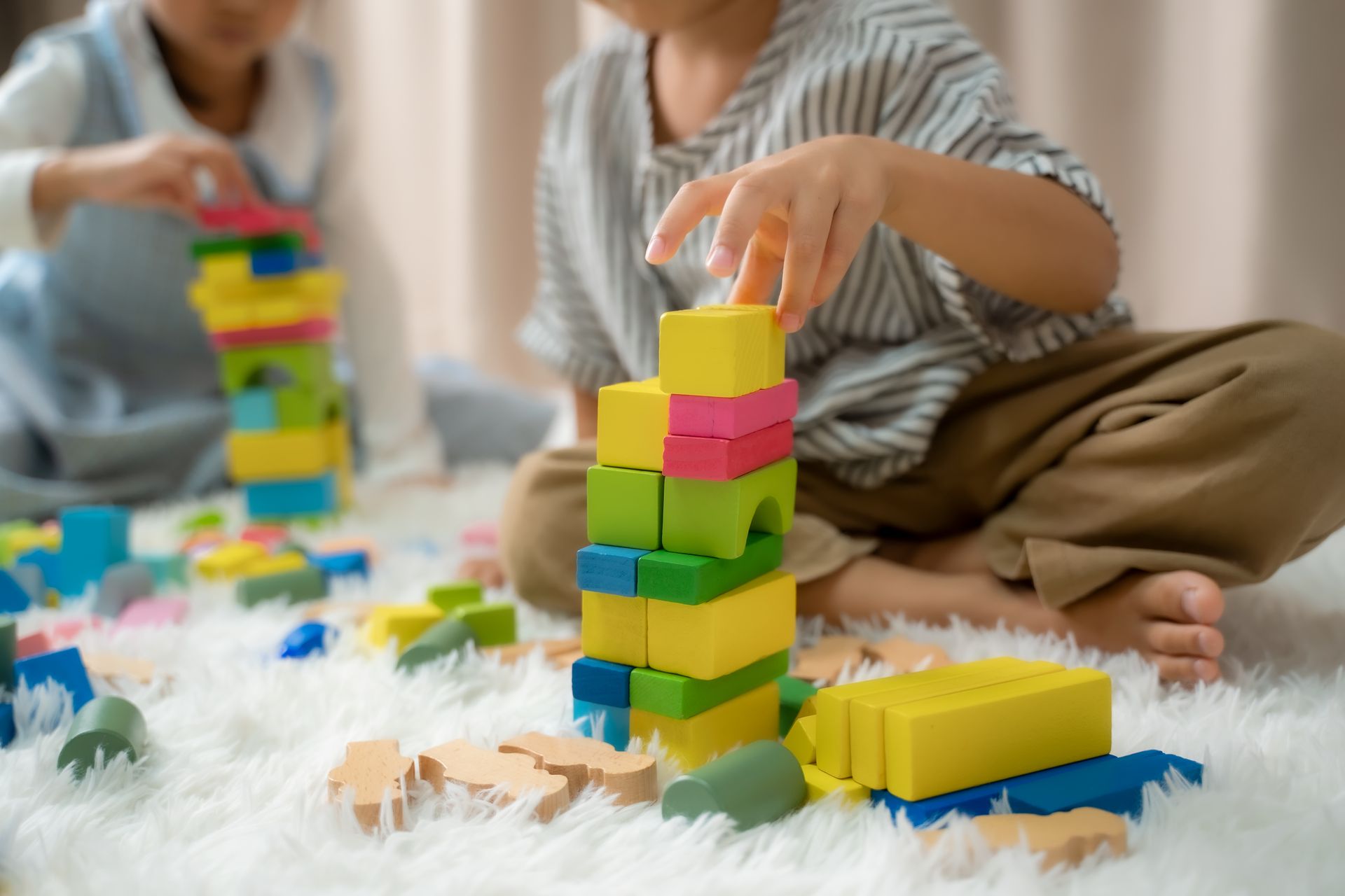 Des enfants empilent des blocs colorés sur un tapis
