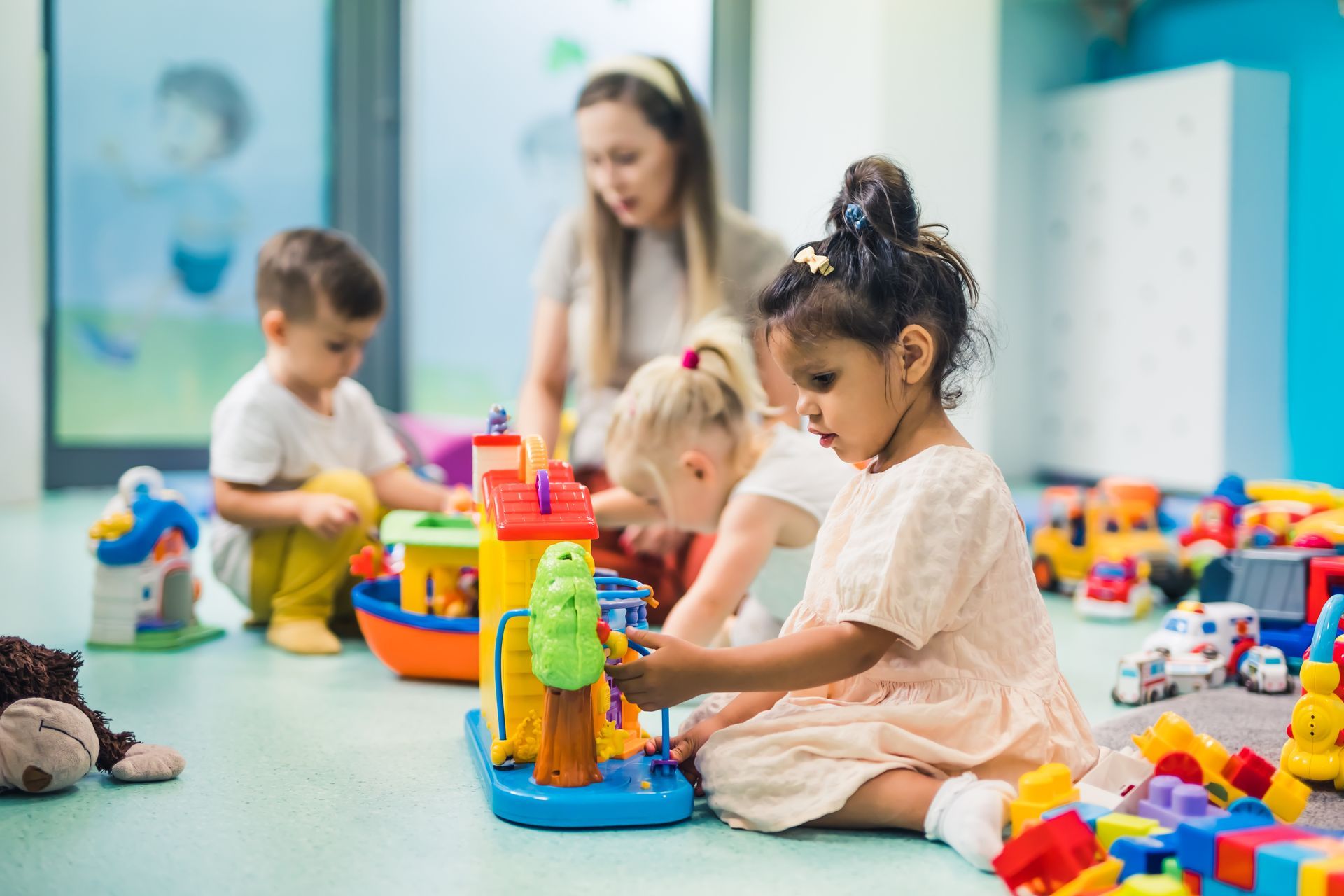 Des enfants et une jeune animatrice jouent avec des jouets colorés dans une crèche