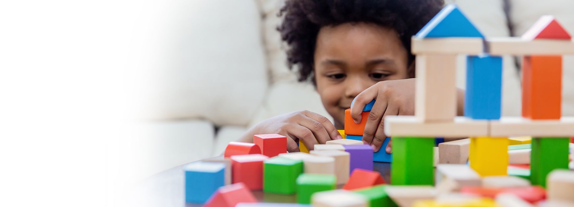 Un enfant assemble des blocs de bois colorés sur une table