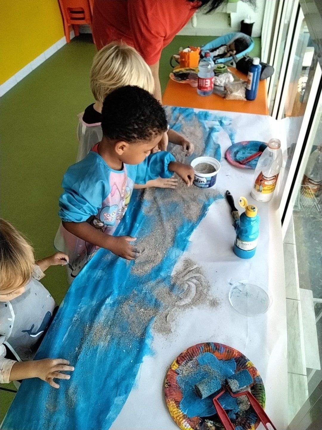 Des enfants assis sur un tapis ; une petite fille tient une peluche en forme chien