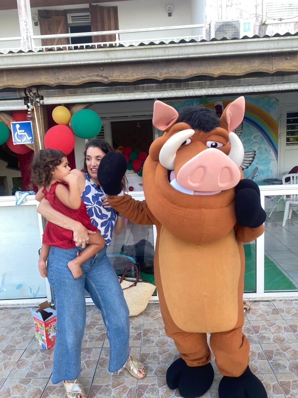 Une petite fille souriante pointe son cahier à l'aide d'un feutre rose