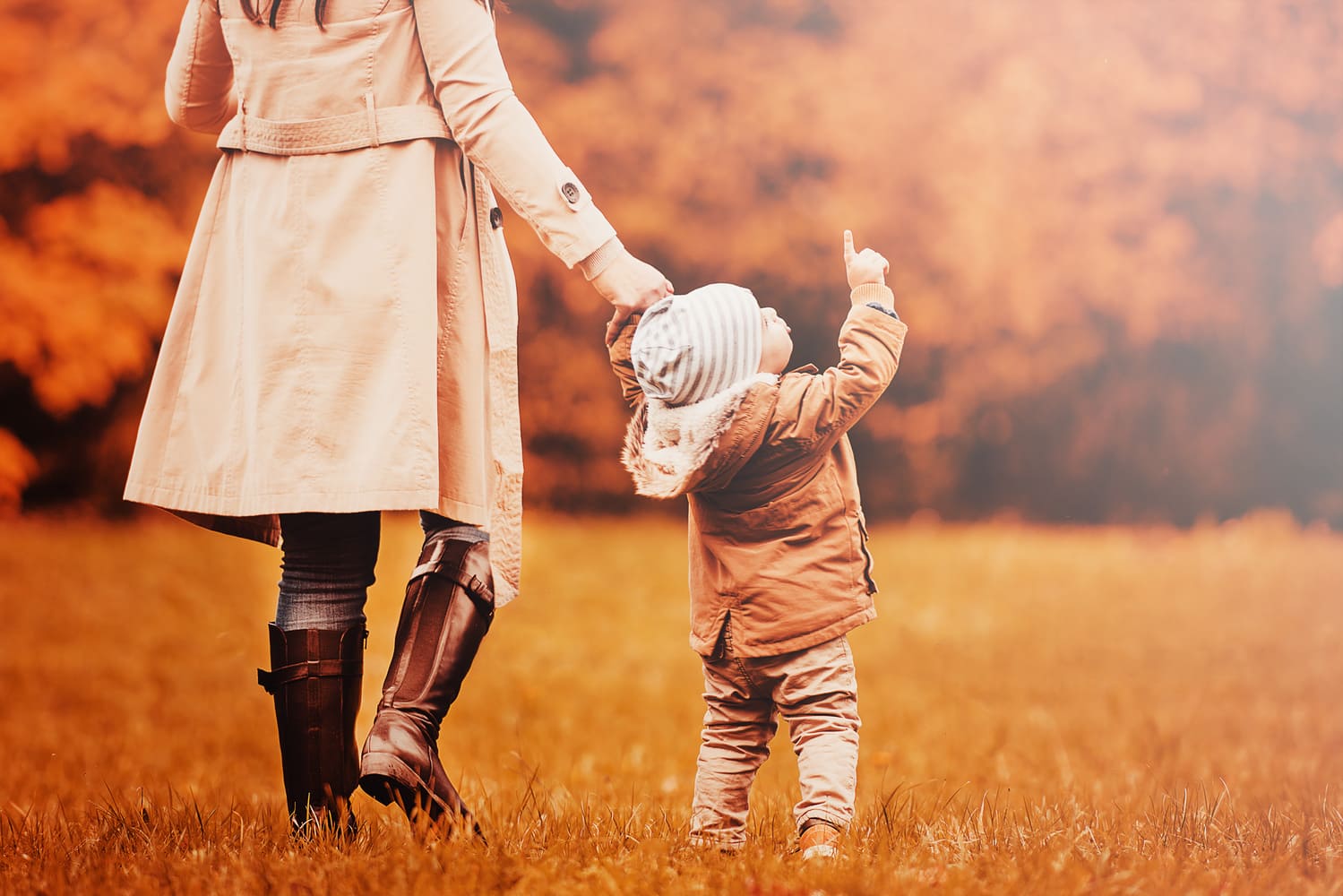 Enfant pointant le ciel du doigt tout en tenant la main d'une adulte