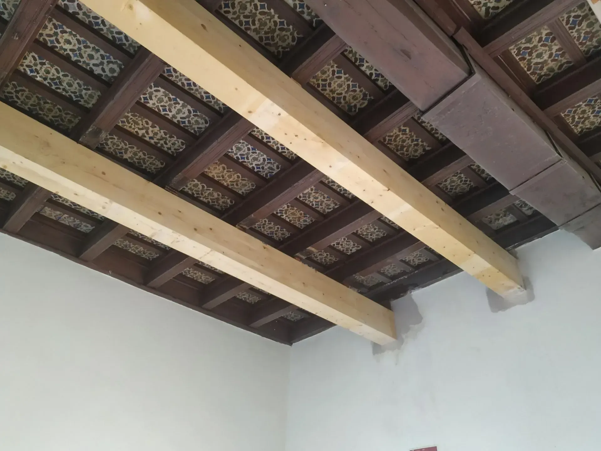 Vigas de madera en el techo y paneles estampados sobre paredes blancas en una habitación