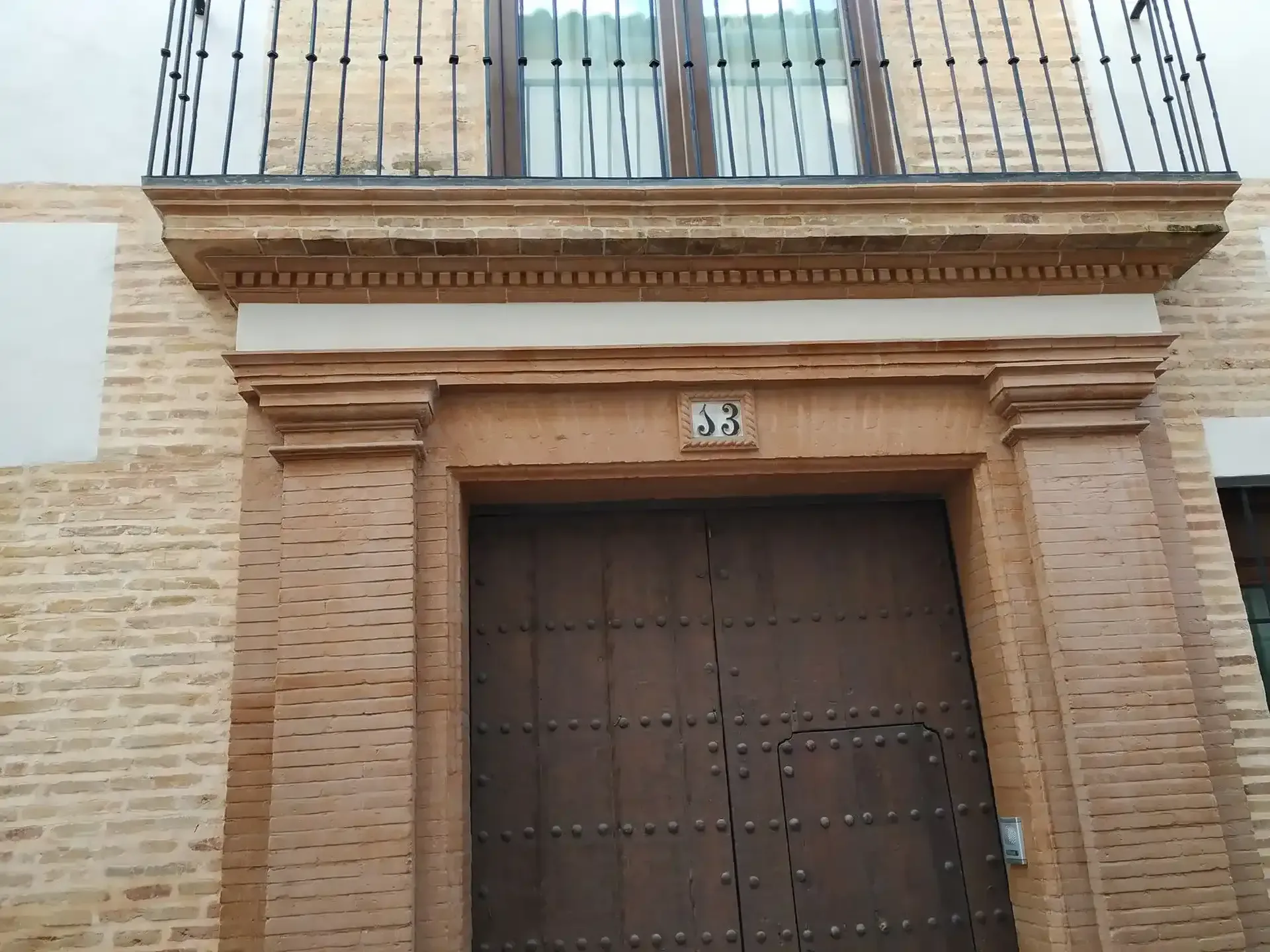 Fachada de un edificio con una gran puerta de madera y un balcón encima, número 38.