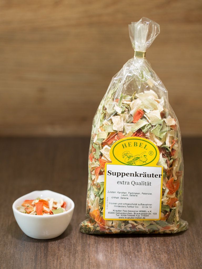 Ein Beutel mit getrockneten Suppenkräutern neben einer kleinen weißen Schüssel auf einem Holztisch