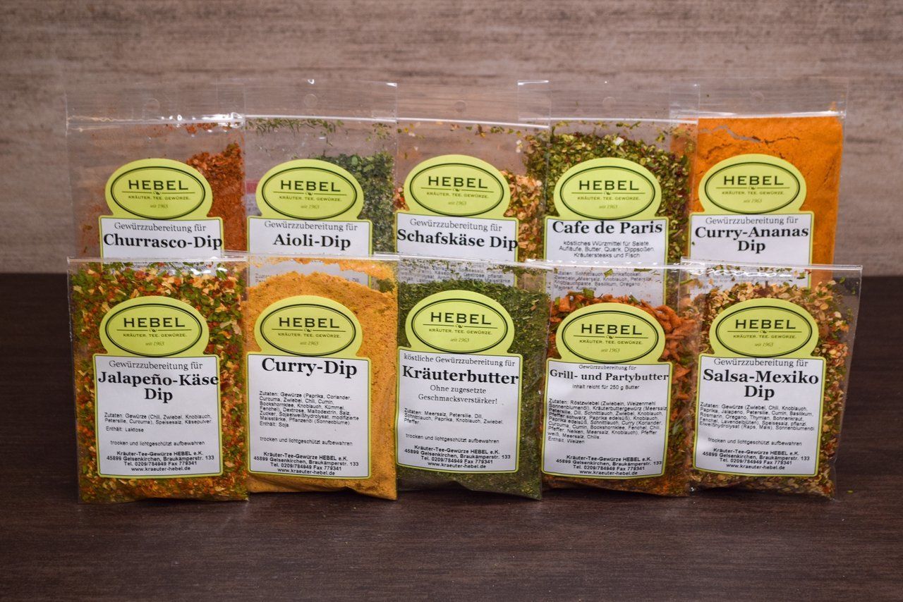 Verschiedene HEEELE-Kräuterteepackungen sind in zwei Reihen auf einem Holztisch angeordnet.