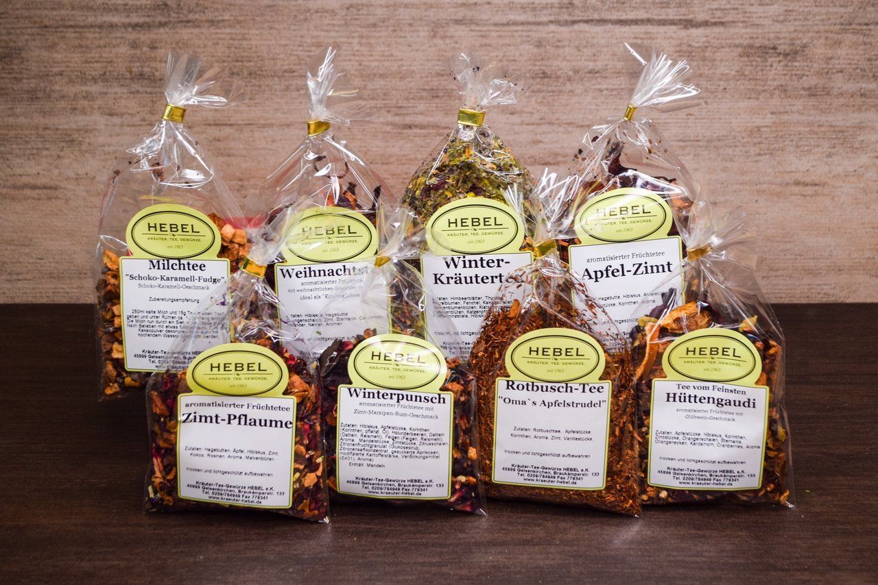 Auf einem Holztisch arrangiert sind Geschenktüten mit verschiedenen Trockenfrüchten und Snacks.