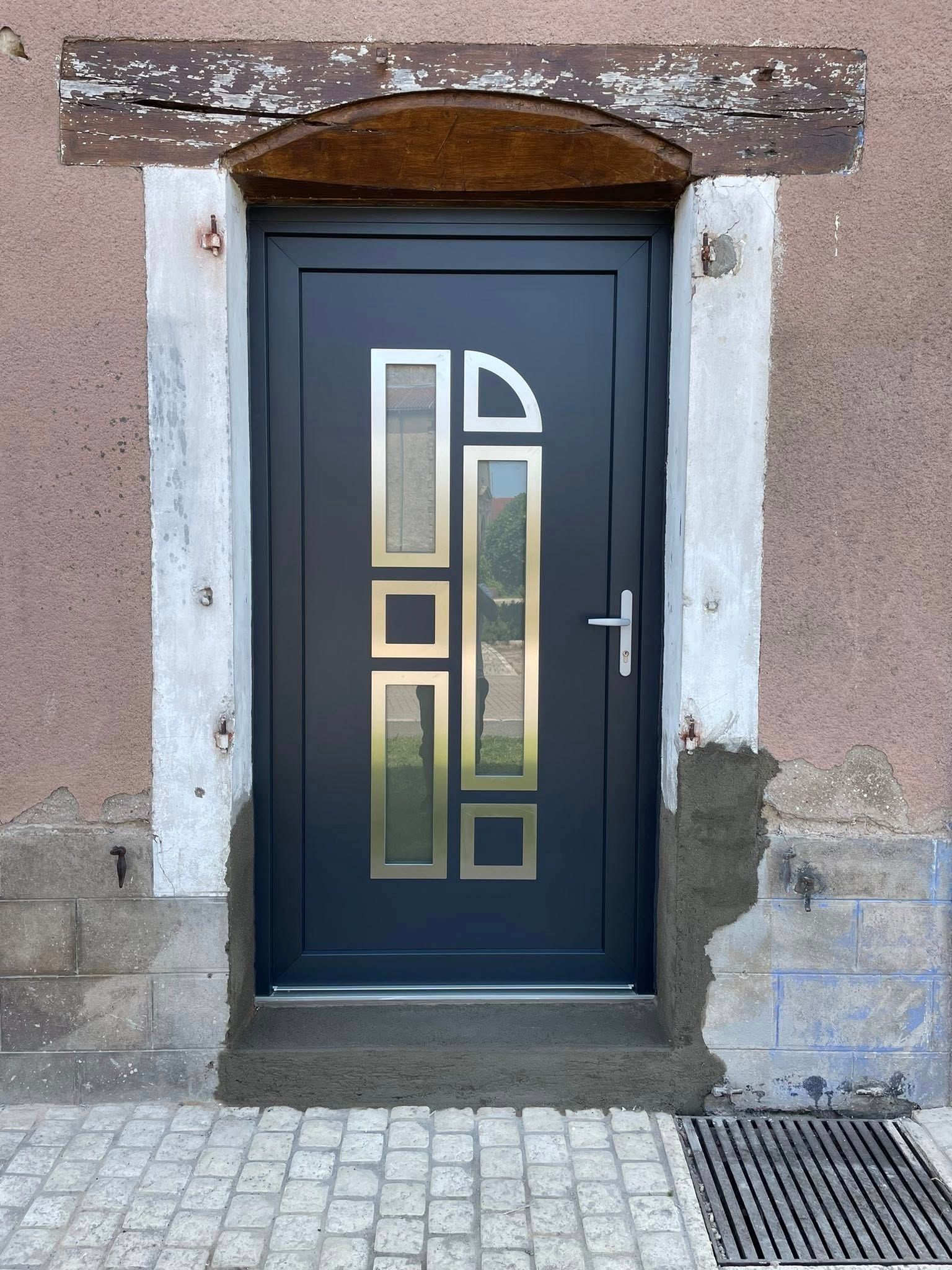 Porte d'entrée bleu foncé avec panneaux de verre décoratifs dans un encadrement en pierre.