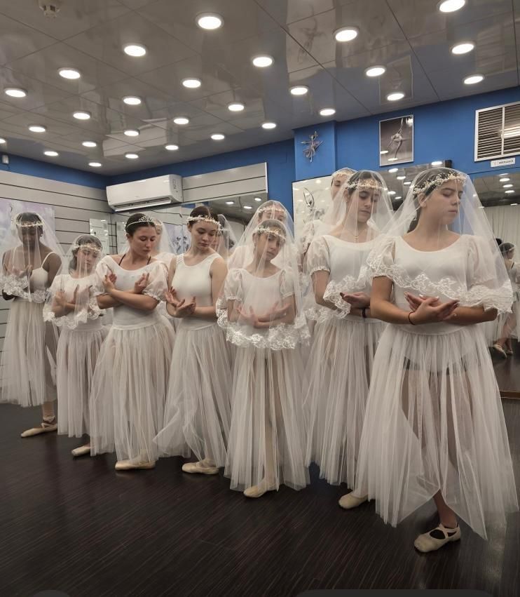 Bailarines de ballet con vestidos blancos y velos practican en un estudio.