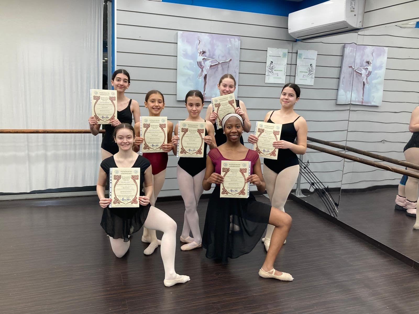 Grupo de jóvenes bailarines de ballet con certificados en un estudio de danza.