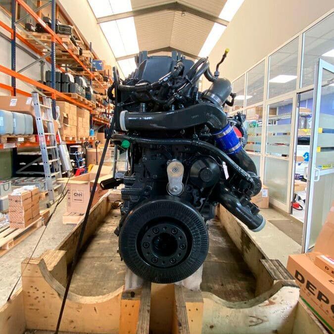 Un gran motor negro está sentado sobre una plataforma de madera en un almacén.