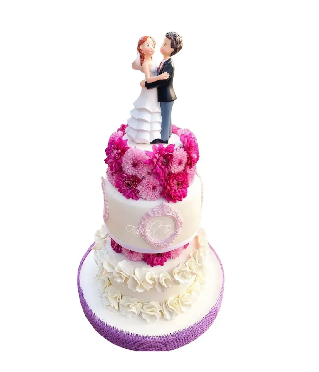 Tarta de boda decorada en blanco y rosa con una figura de novios en la parte superior y flores rosas.