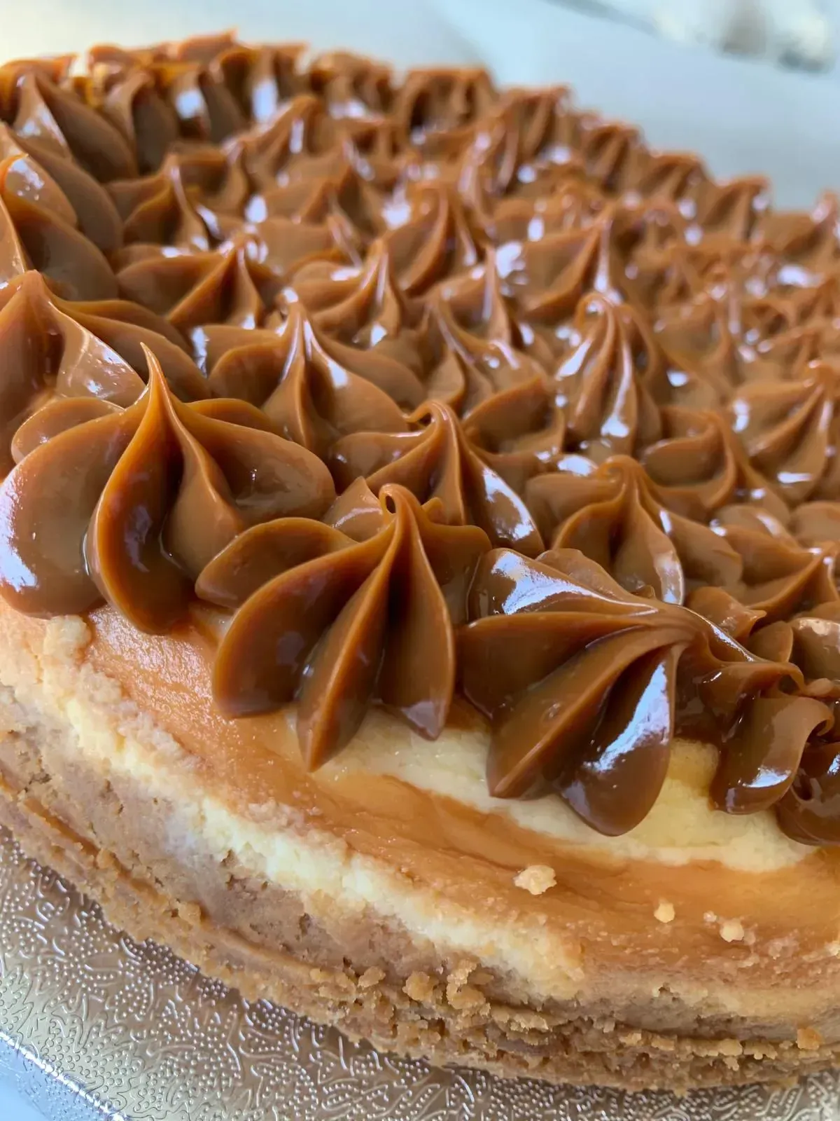 Primer plano de un pastel de caramelo en capas decorado con flores de glaseado de caramelo hechas con manga pastelera.