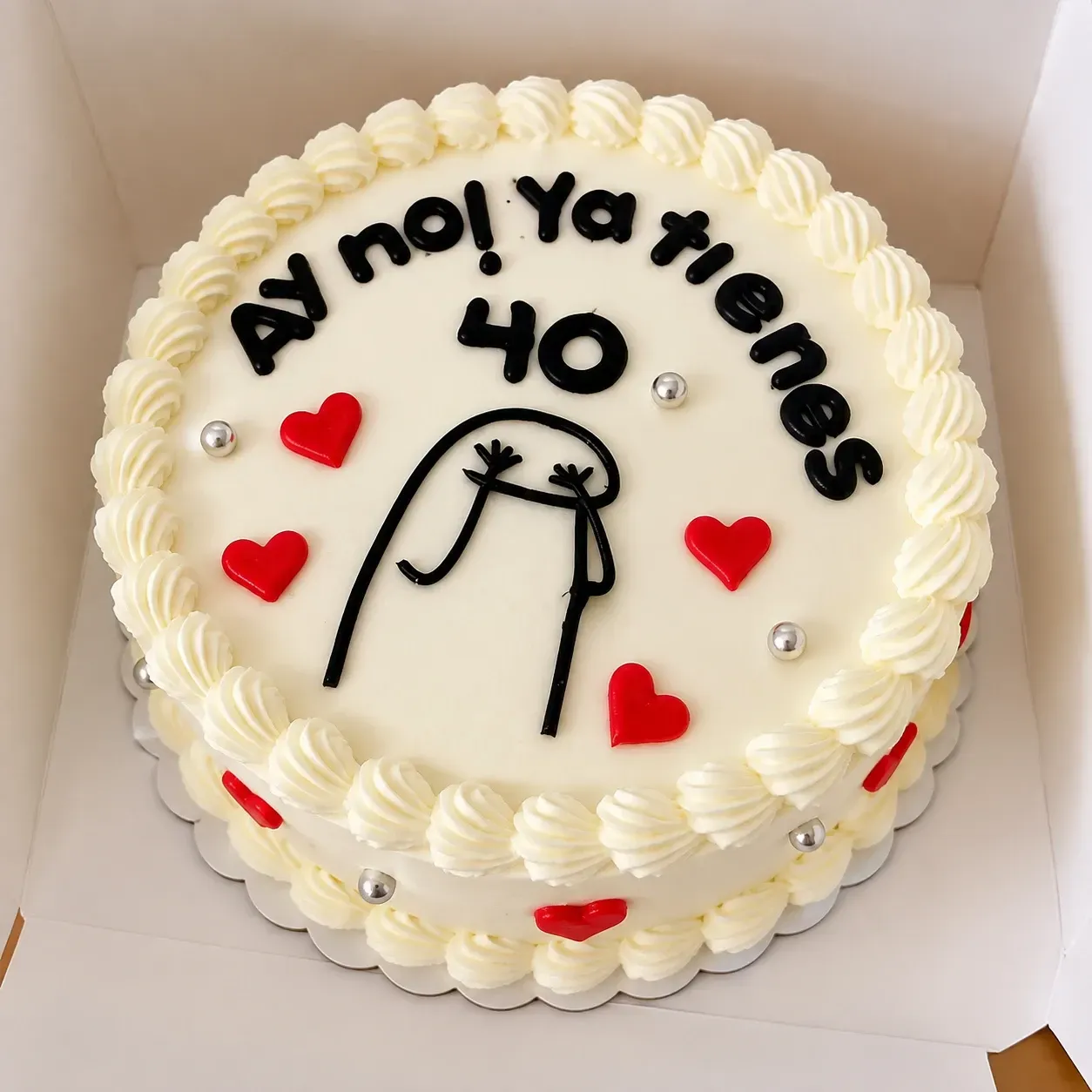 Pastel redondo blanco con texto negro “Ay no! Ya xie es”, el número 40 y corazones rojos en una caja.