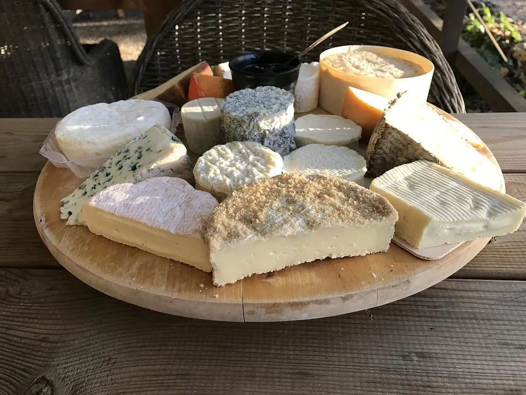 Plateau de fromages variés présentés sur un plateau en bois, en extérieur.
