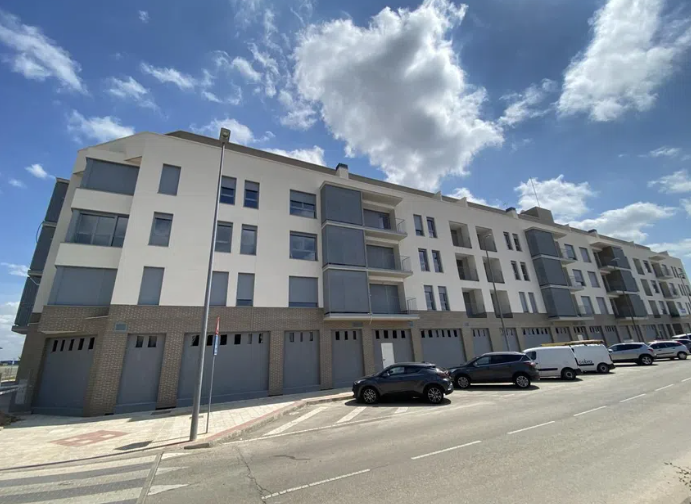 Un gran edificio con coches aparcados delante.