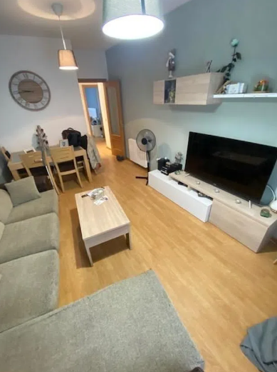 Una sala de estar con un sofá, una mesa y un televisor de pantalla plana.