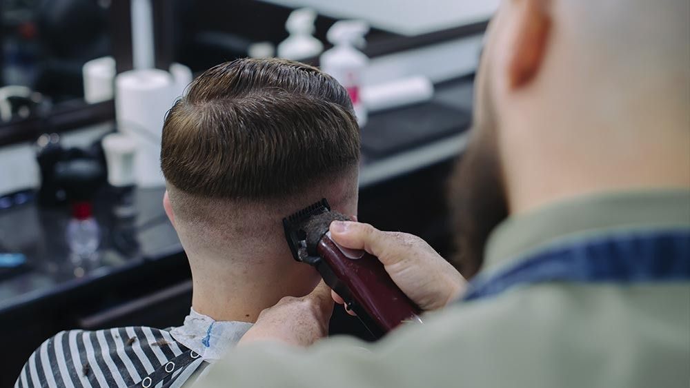 Un hombre se está cortando el pelo con una máquina barbera.