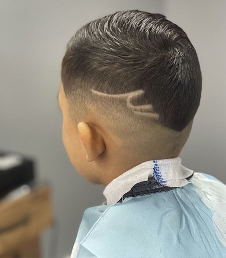Un niño pequeño con un diseño rapado en el cabello.