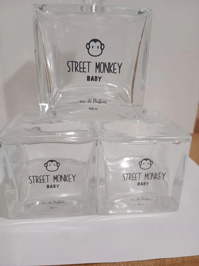 Tres botellas de perfume para bebés de Street Monkey están apiladas una encima de otra sobre una mesa.