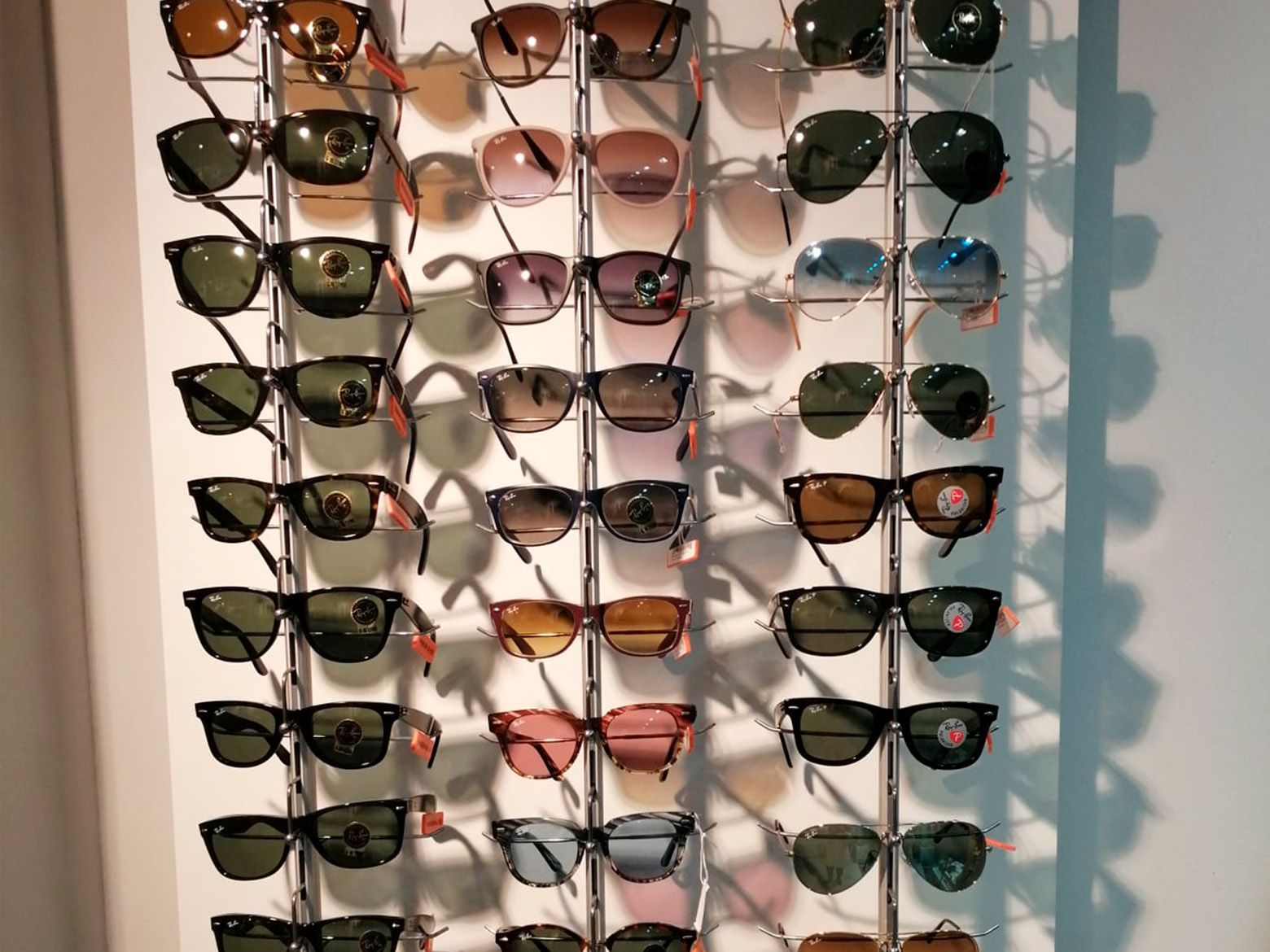 Un montón de gafas de sol están colgadas en una pared.