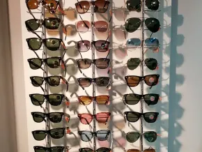 Un montón de gafas de sol están colgadas en una pared.