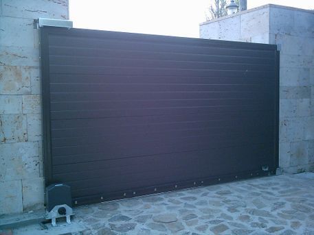 Puerta corredera horizontal de color marrón oscuro en una abertura de pared de piedra.